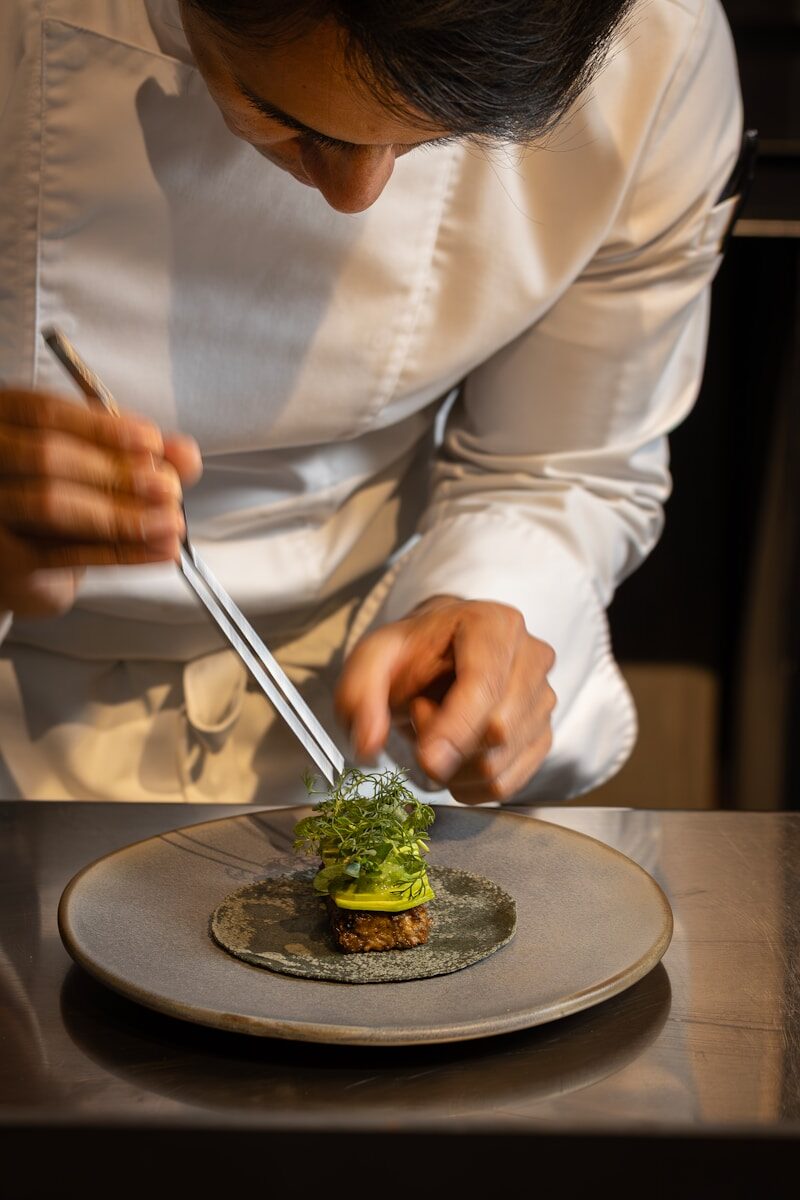 Chef meticulously garnishes a gourmet dish with fresh herbs.